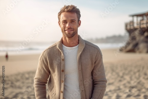 Portrait of handsome young man standing on the beach and looking at camera