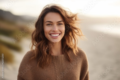 Portrait of a beautiful young woman smiling on the beach in autumn