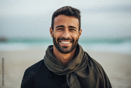 Portrait of a smiling man wearing a scarf on the beach.