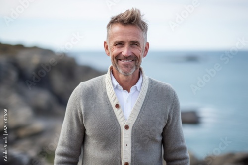 Portrait of smiling mature man standing by seaside in the sunshine