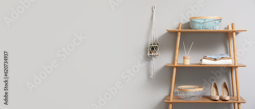Wooden shelving unit with female clothes and shoes near light wall. Banner for design