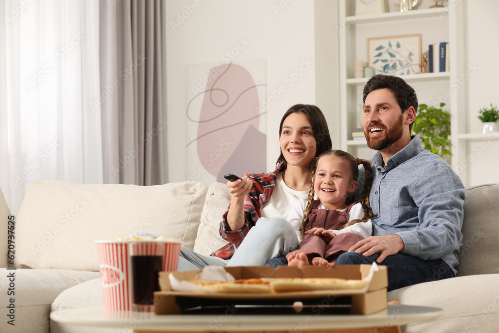 Happy family watching TV with popcorn and pizza on sofa at home Happy family watching TV with popcorn and pizza on sofa at home