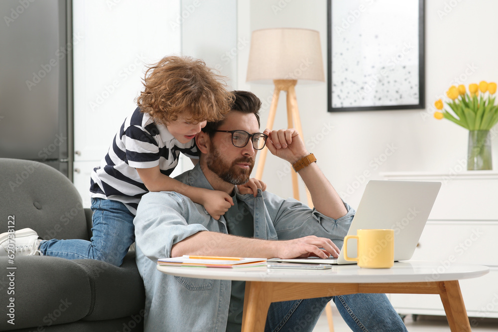 Man with laptop working remotely at home. Father and son at desk Man with laptop working remotely at home. Father and son at desk