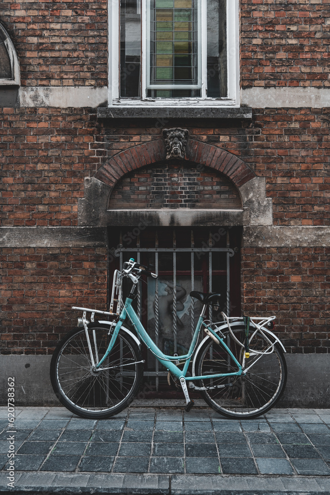 A blue bike parked in an alley in Brugge A blue bike parked in an alley in Brugge