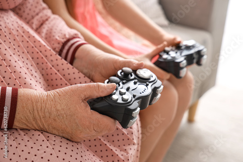 Little girl with her grandmother playing video game at home, closeup