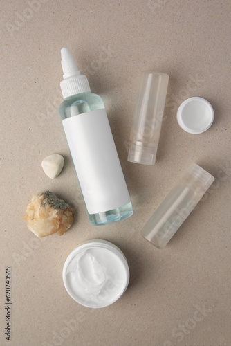 Different cosmetic products and stones on beige background, flat lay