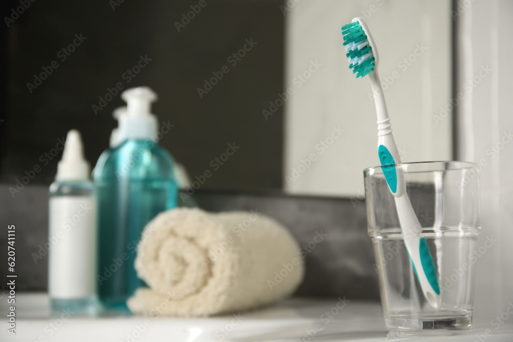 Light blue toothbrush in glass holder on table, space for text Light blue toothbrush in glass holder on table, space for text