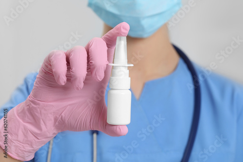 Doctor holding nasal spray on white background, closeup