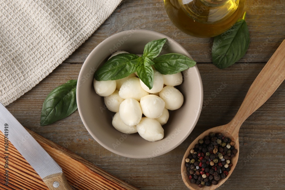 Tasty mozarella balls, basil leaves, oil and spices on wooden table, flat lay Tasty mozarella balls, basil leaves, oil and spices on wooden table, flat lay