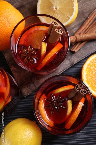 Aromatic punch drink and ingredients on black table, flat lay