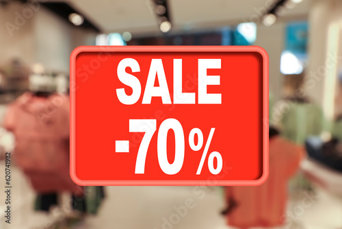 Sale sign and blurred view of fashion store with clothes