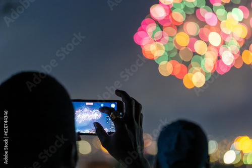 Man taking a cellphone video of fireworks on 4th of July