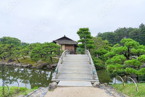 きれいに手入れされた日本庭園で見た古い茶室と木製太鼓橋のコラボ情景