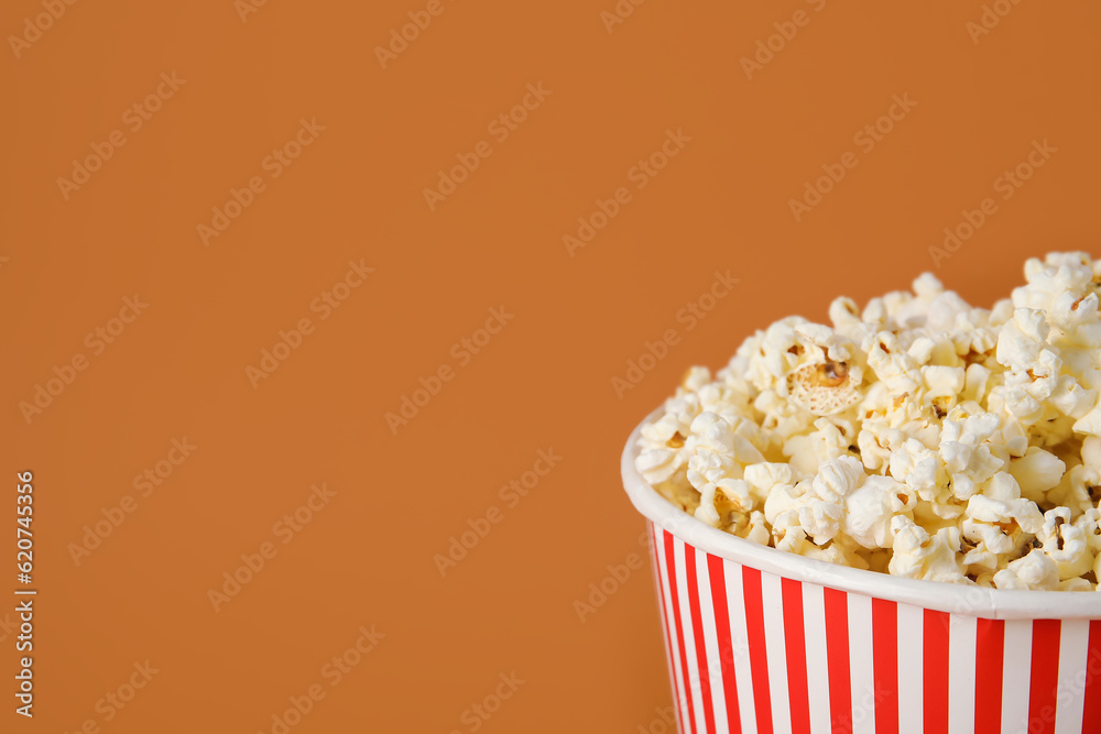 Bucket with tasty popcorn on brown background