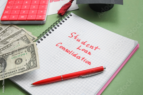 Notebook with text STUDENT LOAN CONSOLIDATION, calculator and dollar banknotes on green background