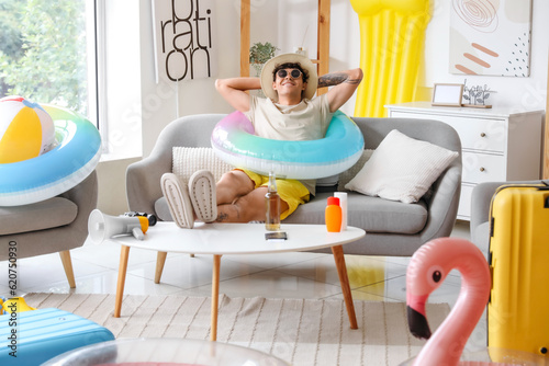 Sticker Young man with beach accessories ready for summer vacation at home