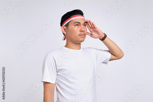 Handsome Asian man giving salute celebrate Indonesian independence day on 17 August isolated over white background
