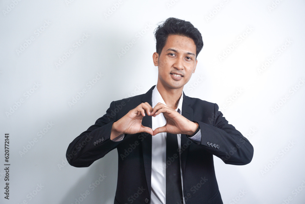 Portrait of smiling young man keeps hands on chest in heart shape sign, expresses sympathy. Kind hearted friendly nice guy wearing suit Portrait of smiling young man keeps hands on chest in heart shape sign, expresses sympathy. Kind hearted friendly nice guy wearing suit