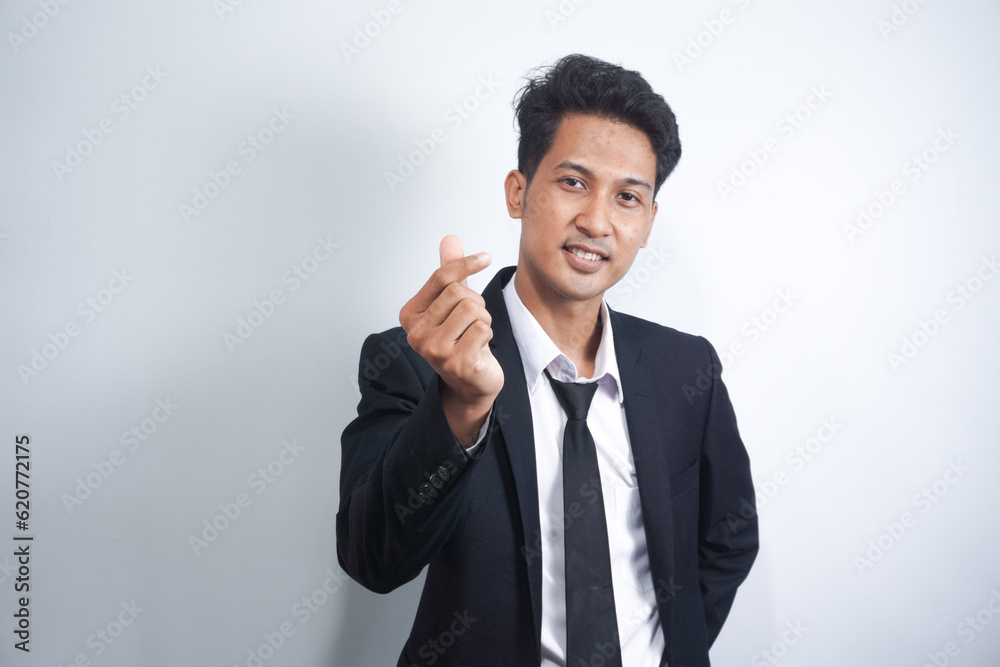 Young Asian business man wearing suit giving Korean love symbol with your fingers. Hands represent heart. Young Asian business man wearing suit giving Korean love symbol with your fingers. Hands represent heart.