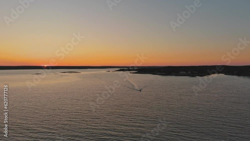 A boat speeds across the water against the setting sun photo