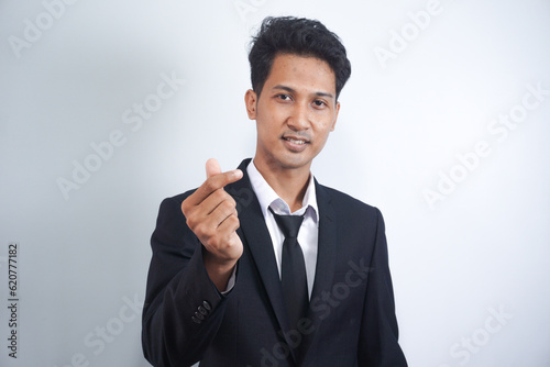 Young Asian business man wearing suit giving Korean love symbol with your fingers. Hands represent heart.