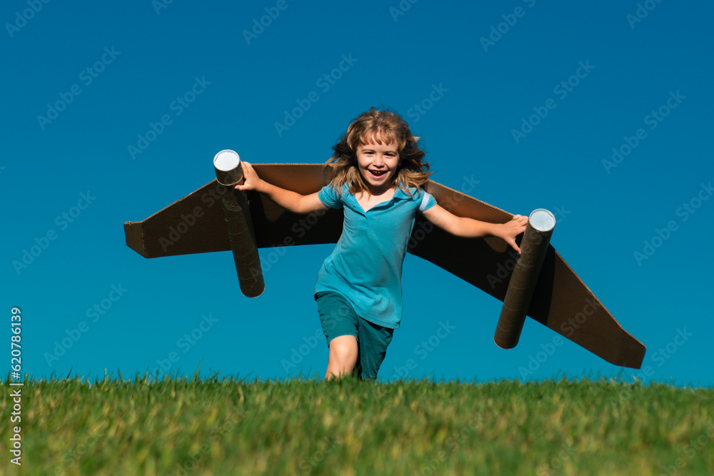 Child run with paper wings against blue sky. Kid dreams of future. Kid pilot dreaming. Childhood dream concept. Blonde cute daydreamer child dream on fly. Dreams and imagination. Creative kid.