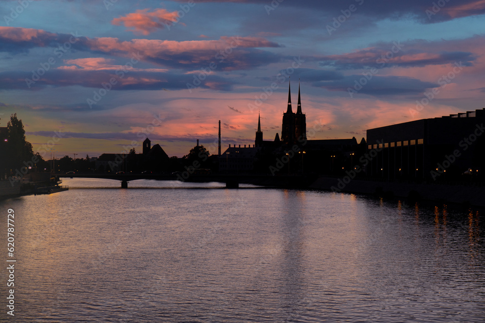 Fototapeta premium Panoramic evening view on Wroclaw Old Town. Silhouette of Island and Cathedral of St John with bridge through river Odra. Wroclaw, Poland. Grunwaldzki bridge over the Odra river