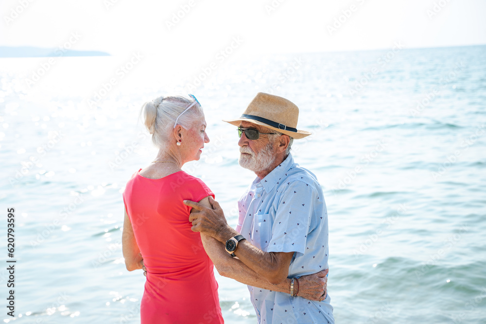 Happy senior couple walking together on beach on beautiful day,Authentic Senior Retired Life Concept
