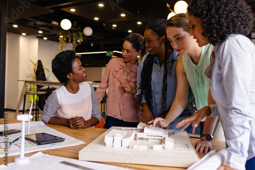 Diverse female architects in discussion using model and blueprints in casual office meeting © wavebreak3