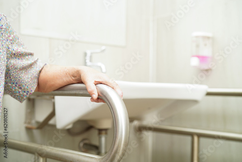Canvastavla Asian elderly old woman patient use toilet support rail in bathroom, handrail safety grab bar, security in nursing hospital