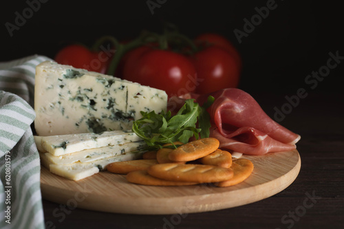 Cheese and cold cuts on a wooden tray on a wooden table
