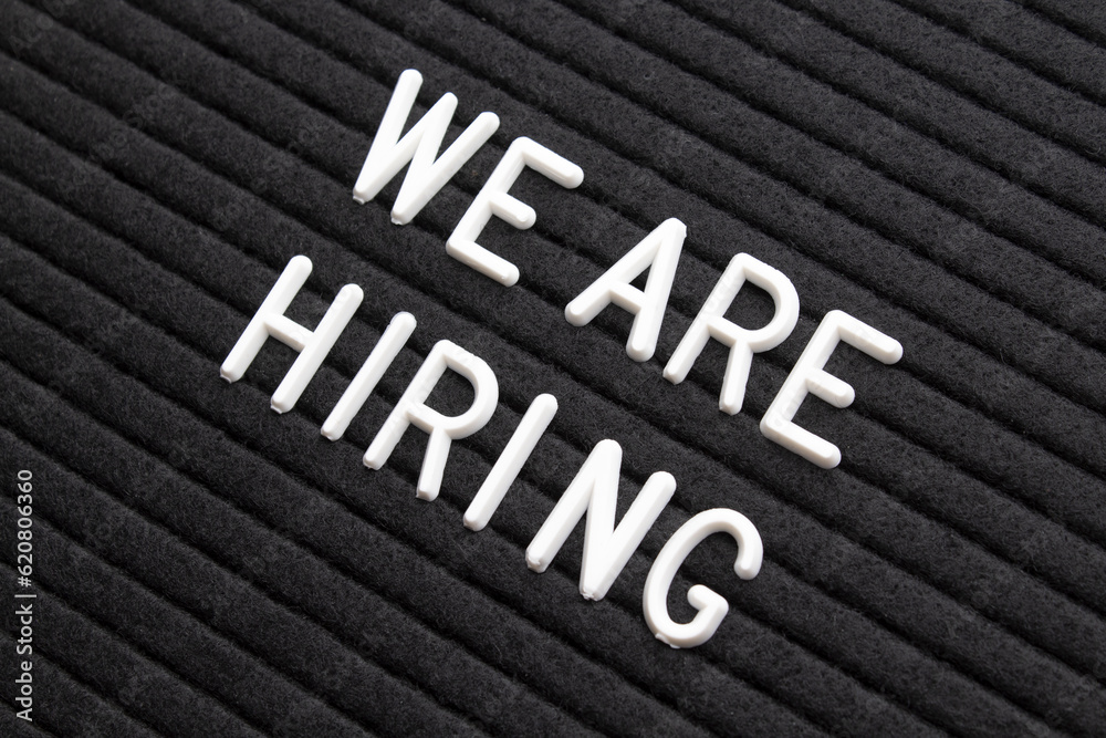 The phrase we are hiring on black letter board The phrase we are hiring on black letter board