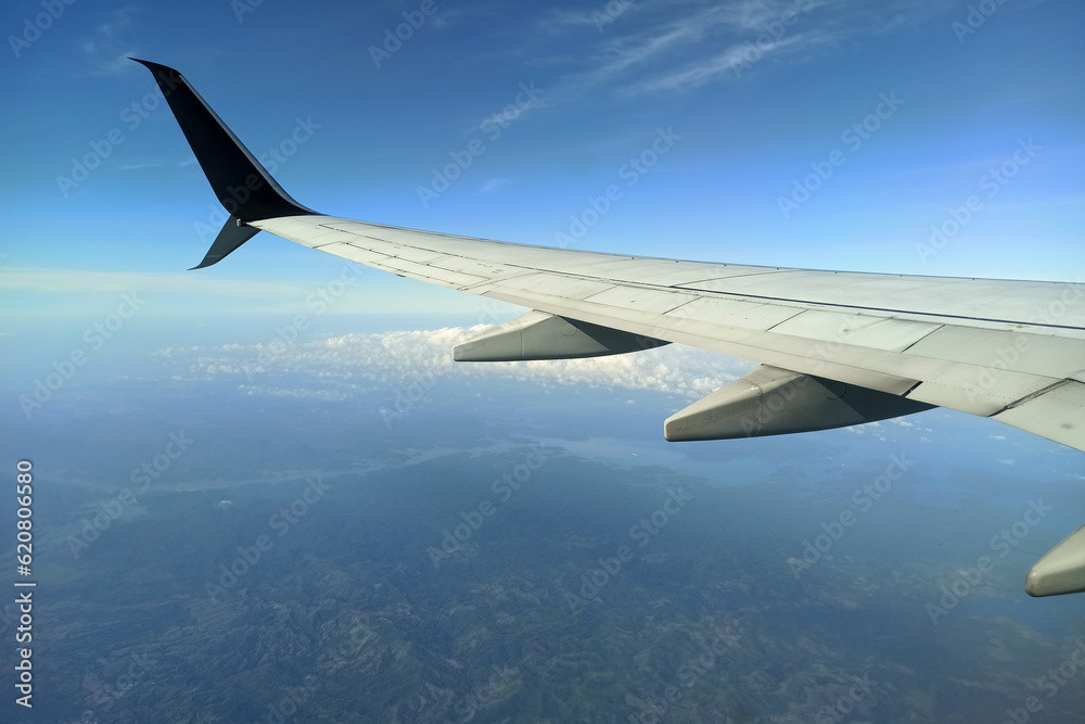 Fototapeta premium View through airplane window of commercial jet plane wing flying high in the sky. Air travelling concept