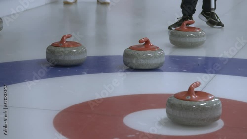 Curling stone hitting two other stones, bouncing the opposite team's stone out of the house. photo