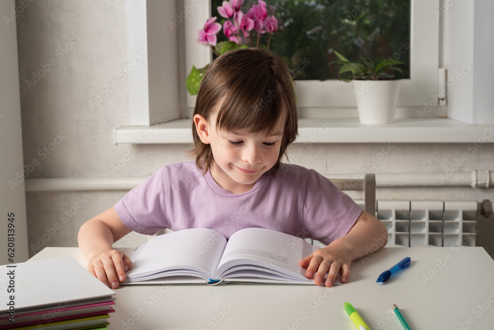 Back to school. The girl is sitting at the table and reading a book. Children learning at home Back to school. The girl is sitting at the table and reading a book. Children learning at home