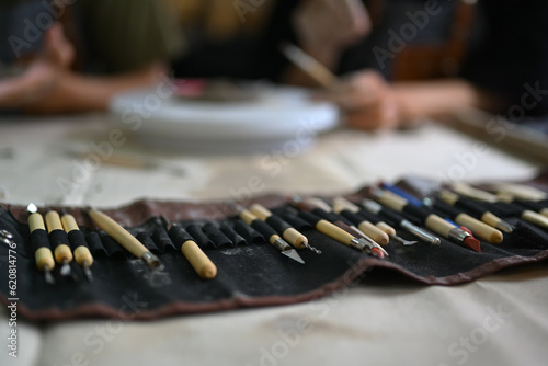 Closeup shot of various tools for pottery on table in workshop. Handicraft, creativity, hobby and activity concept