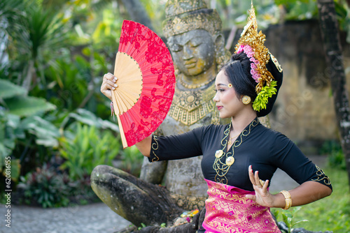 Woman poses in front of a Buddha statue in a traditionally costume and a crown in hair photo