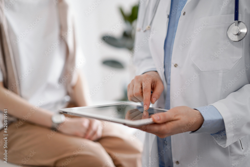 Doctor and patient in clinic. Friendly physician using tablet computer near a young woman. Medicine concept Doctor and patient in clinic. Friendly physician using tablet computer near a young woman. Medicine concept
