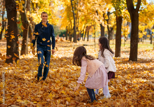 portrait of a big family in autumn city park, happy parents and children playing together and throwing yellow leaves, beautiful nature, bright sunny day