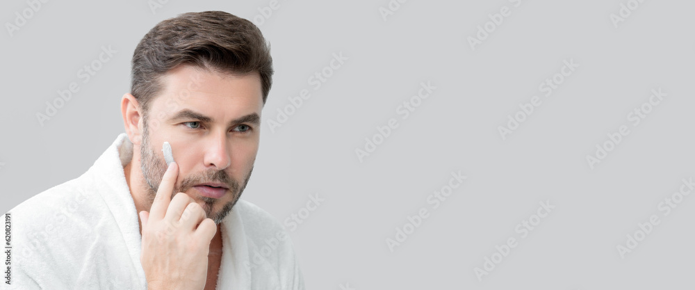 Fototapeta premium Banner of man with perfect skin touch face after shaving. Skin care healthcare cosmetic procedures concept. Close up man looking in mirror, sensitive skin, cosmetology treatment. Skin care.