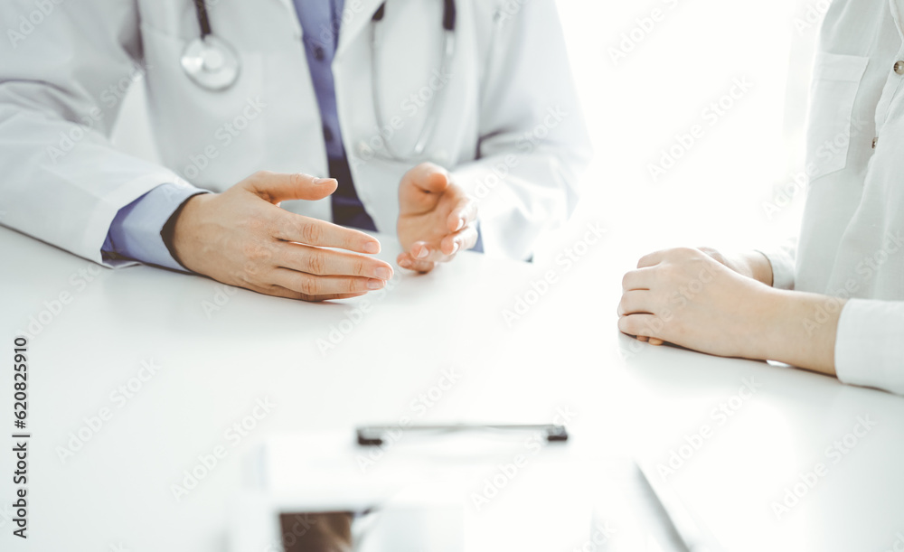 Doctor and patient discussing current health questions while sitting near of each other at the table in clinic, just hands closeup. Medicine concept Doctor and patient discussing current health questions while sitting near of each other at the table in clinic, just hands closeup. Medicine concept