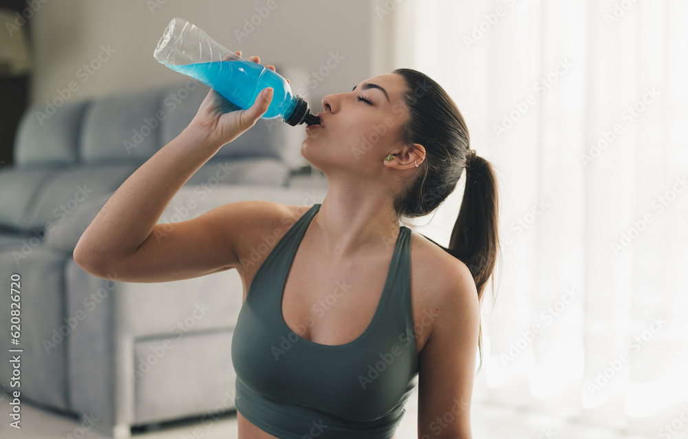 Young woman drinking water during break in yoga workout in room Young woman drinking water during break in yoga workout in room