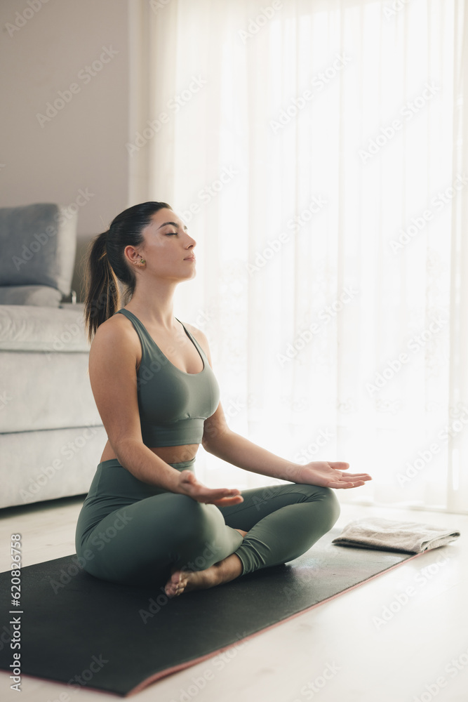 Woman meditating in Padmasana pose at home