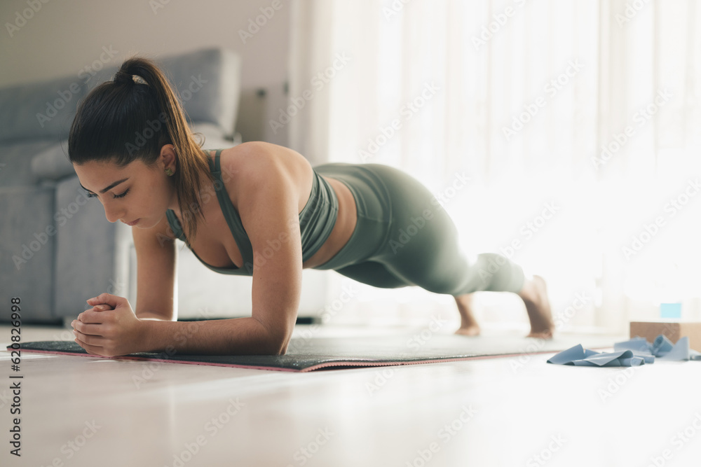 Slim woman doing plank exercise on mat at home Slim woman doing plank exercise on mat at home