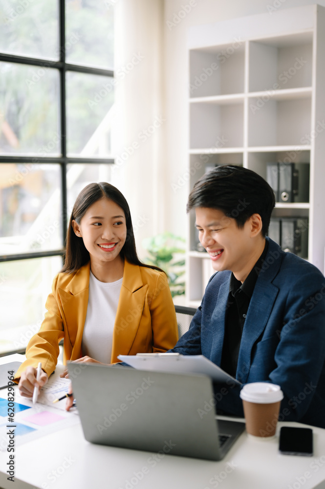 Two Asian business man and woman workers talking on the smartphone and using laptop Professionals in Teamwork Finance, Marketing, and Success Two Asian business man and woman workers talking on the smartphone and using laptop Professionals in Teamwork Finance, Marketing, and Success
