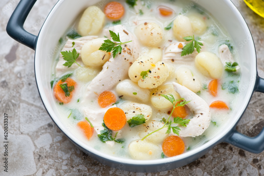 Creamy soup with chicken fillet and potato gnocchi in a grey serving pan, middle close-up, horizontal shot, selective focus Creamy soup with chicken fillet and potato gnocchi in a grey serving pan, middle close-up, horizontal shot, selective focus