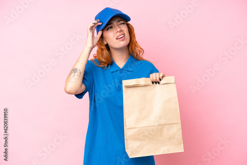 Young caucasian woman taking a bag of takeaway food isolated on pink background having doubts and thinking