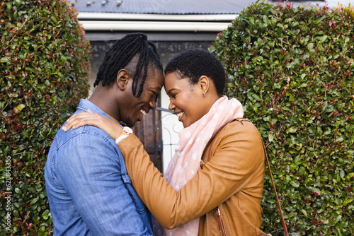 Side view of romantic african american couple looking at each other while standing outside house photo