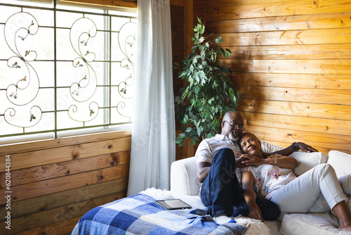 Senior african american couple lying on sofa and embracing at home photo