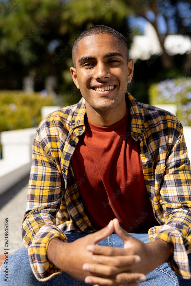 Portrait of happy biracial man sitting in sunny garden smiling Portrait of happy biracial man sitting in sunny garden smiling